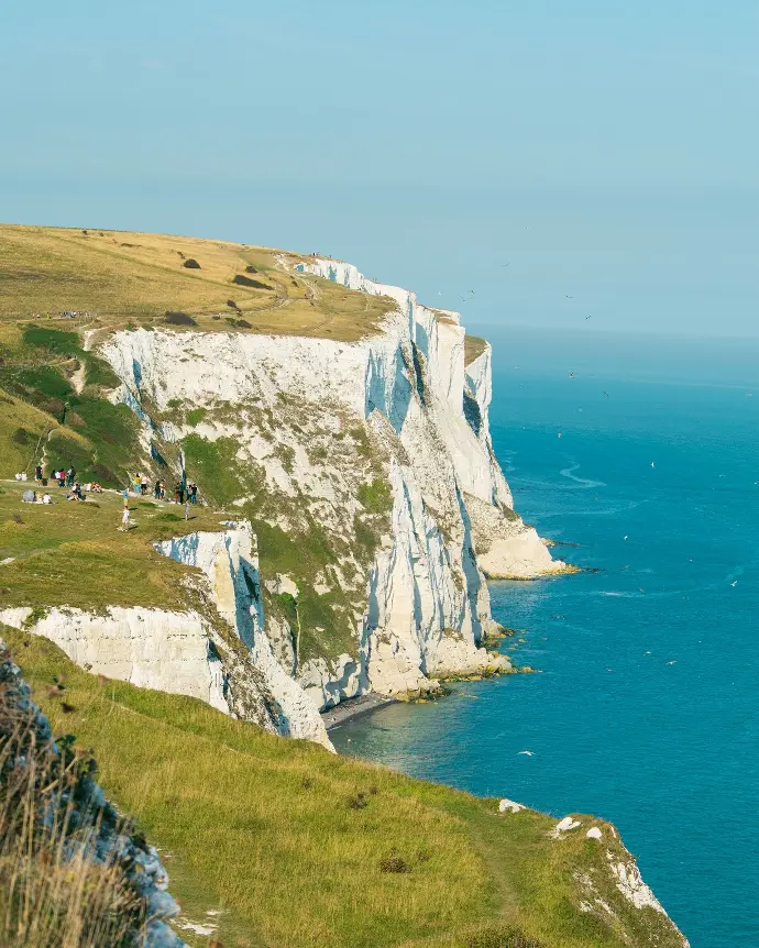 white and green mountain beside blue sea during daytime